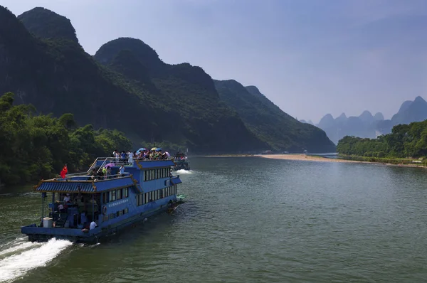 Passagier boten met toeristen in de Li rivier waar de hoge kalkstenen pieken op de achtergrond in de buurt van Yangshuo in China — Stockfoto