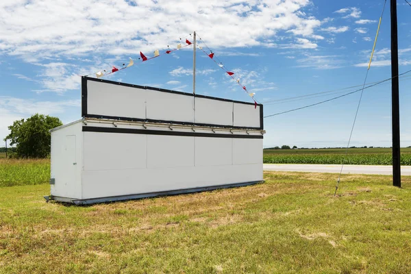 White billboard along a country road in rural Texas with a corn field on the background