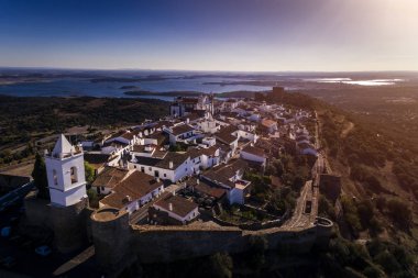 Aerial view of the historic village of Monsaraz in Alentejo with the Alqueva dam reservoir on the background; Concept for travel in Portugal and Alentejo clipart
