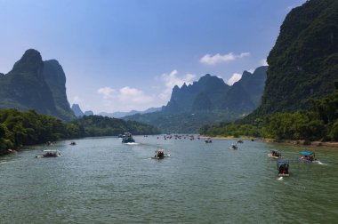 Yangshuo, Çin - 1 Ağustos 2010: Tekne turist Yangshuo Çin, Asya yakın planda uzun boylu kireçtaşı zirveleri ile Li Nehri seyir.