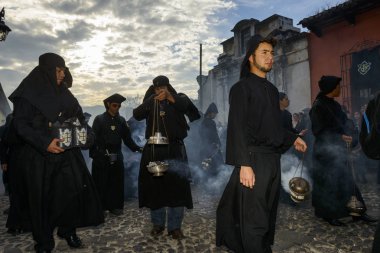 Antigua, Guatemala - 19 Nisan 2014: siyah elbiseler ve tütsü Antigua şehir bir sokakta bir alay Antigua, Guatemala kutsal hafta sırasında yayılan davlumbaz giyen adam