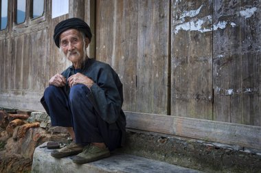 Dazhai, Çin - 4 Ağustos 2012: Çin, Asya Dazhai köy içinde eski bir binanın kapısında oturan yaşlı bir Çinli adam