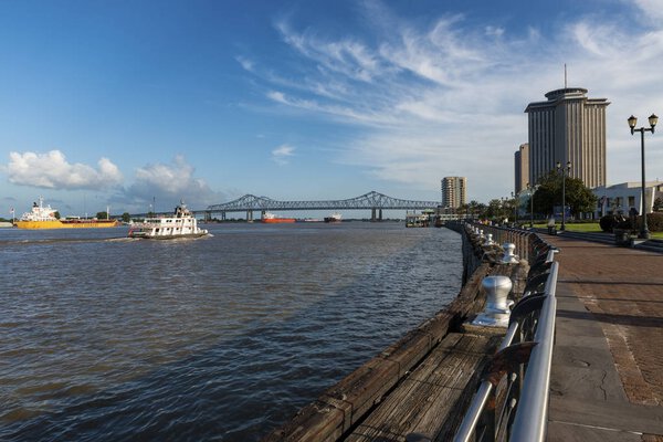 New Orleans, Louisiana - June 17, 2014: View of the Mississippi river with boats from the city of New Orleans riverfron, with the Great New Orleans Bridge on the background in New Orleans, Louisiana, USA.