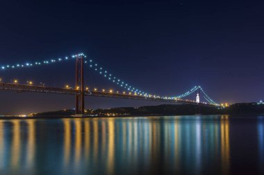 Güzel ve sakin görünümü 25 Nisan Köprüsü (Ponte 25 de Abril) gece, Lizbon, Portekiz ve Tagus Nehri; Ziyaret Lizbon için kavram