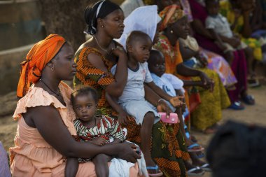 Bissau, Republic of Guinea-Bissau - January 29, 2018: Portrait of a young mother and her baby daughter during a community meeting, at the Bissaque neighborhood in the city of Bissau, Guinea Bissau. clipart