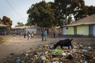 Bissau, Republic of Guinea-Bissau - January 29, 2018: Group of children playing in a dirty street at the Bissaque neighborhood in the city of Bissau, Guinea Bissau. clipart