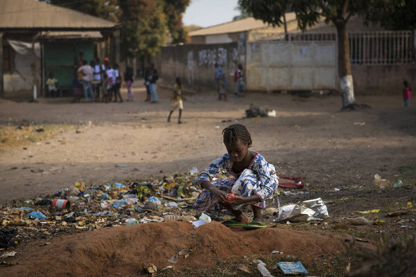 Бисау, Республика Гвинея-Бисау - 29 января 2018 года: Молодая девушка собирает мусор на улице района Бисаке в городе Бисау, Гвинея-Бисау
.