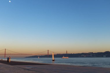 Lisbon, Portekiz - 10 Ocak 2017: Nisan köprüde planda şehir Lizbon, Portekiz (Ponte 25 de Abril) 25 ile Tagus Nehri yakınında günbatımı zevk insanlar