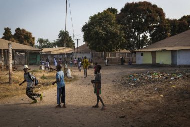 Bissau, Republic of Guinea-Bissau - January 29, 2018: Group of children playing outside their school after the classes, at the Bissaque neighborhood in the city of Bissau, Guinea Bissau. clipart