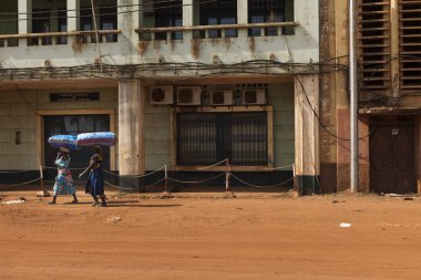 Bissau, Gine Cumhuriyeti - 30 Ocak 2018: iki kadın bir kir sokak başlarına büyük çanta taşıyan yakınındaki Bissau bağlantı noktası. Eski bir Portekiz sömürgesi ve dünyanın en yoksul ülkelerinden Gine Bissau biridir.