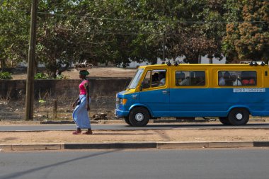 Bissau, Gine Cumhuriyeti - 31 Ocak 2018: bir tepsi kafasını ve Gine Bissau, Batı Afrika halk otobüsü (toca toca) bir kadınla Bissau şehir sokak sahne