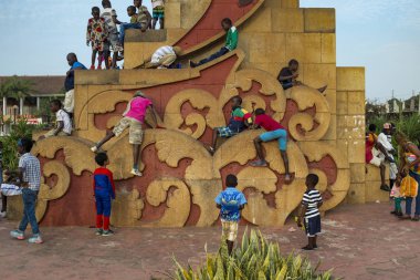 Bissau, Republic of Guinea-Bissau - February 10, 2018: Children playing at a statue in the Praca dos Herois Nacionais, in Guinea-Bissau, West Africa clipart