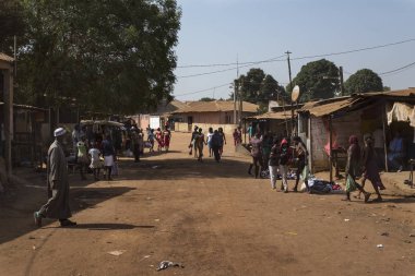 Bissau, Gine-Bissau Cumhuriyeti - 12 Şubat 2018: Bissau, Gine Bissau 'daki bir gecekondu mahallesinde toprak bir sokakta yürüyen insanlar.