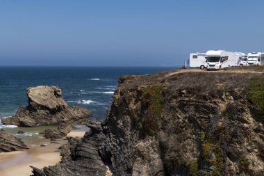Campers parked on a cliff near the village of Porto Covo, in the Costa Vicentina Natural Park in Portugal; Concept for road trip in Portugal and summer vacations clipart
