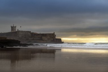 Sao Juliao da Barra Kalesi 'nin olduğu Carcavelos Sahili manzarası gün doğumunda Portekiz' de.
