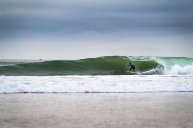 Carcavelos, Portugal - January 9, 2020: A surfer riding a wave at the Carcavelos beach in a winter morning.