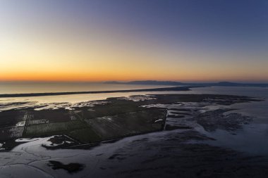 Aerial view of the Sado Estuary near the village of Carrasqueira, with a rice plantation, the Troia Peninsula and the Arrabida Mountain on the background at sunset, in Portugal. clipart
