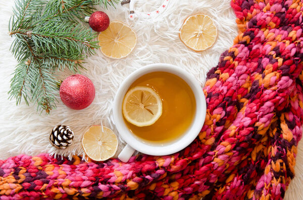 Top view of a red knitted scarf and cup of tea with lemon. Winter mood. Flat lay christmas decoration