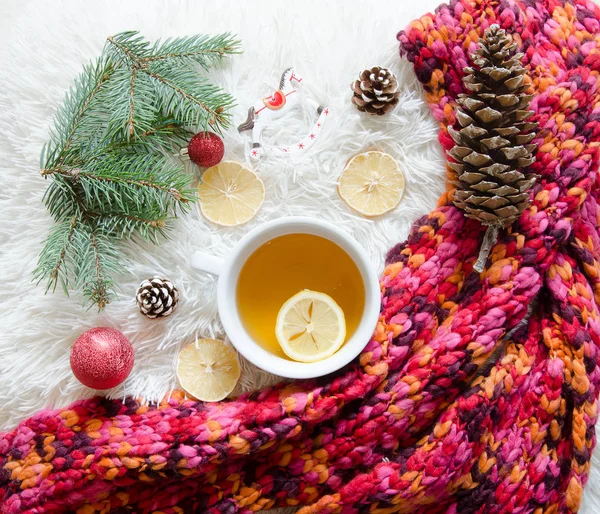 Top view of a red knitted scarf and cup of tea with lemon. Winter mood. Flat lay christmas decoration