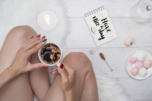 Womans hands with cup of tea, sweets and note book with lettering.Good morning