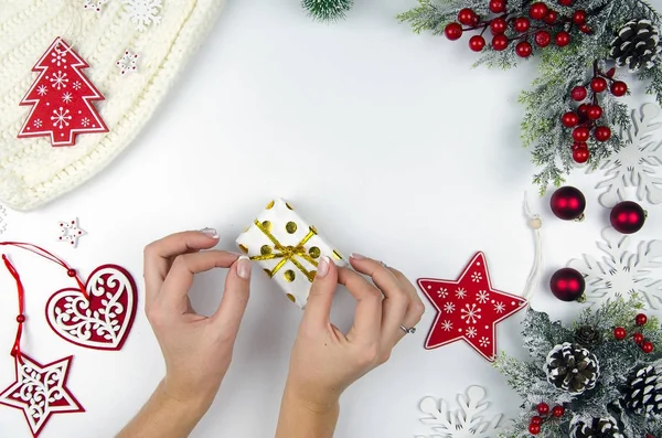 Presente nas mãos da rapariga. Presentes de Natal e Ano Novo. Ramos de abeto e decorações de Natal leigos planos. Espaço de cópia da vista superior — Fotografia de Stock