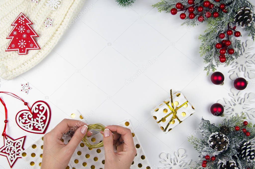 Gift in the hands of the girl. Christmas and New Year gifts. Fir branches and christmas decorations flat lay. Top view copy space