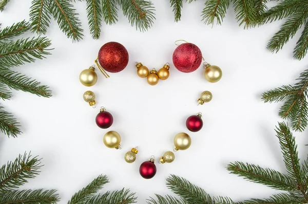 Donna posa palle di Natale a forma di cuore su sfondo bianco con rami di abete. Flatly, vista dall'alto — Foto Stock