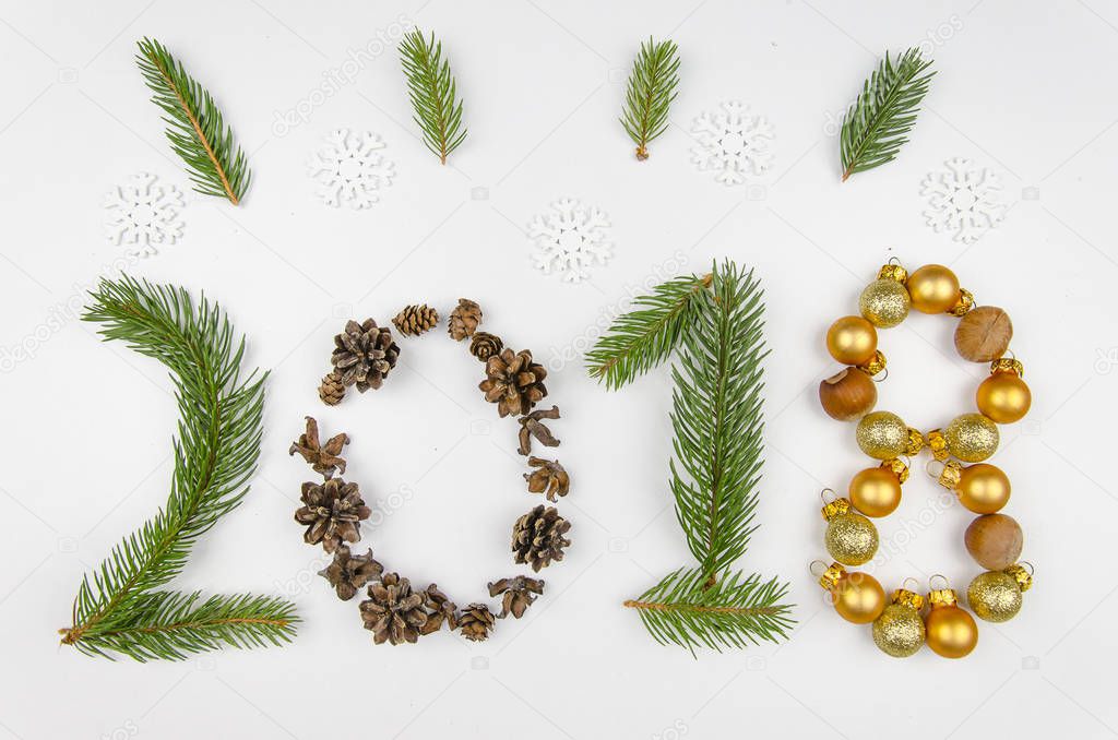 New year figures 2018 made of Christmas tree branch, bumps and Christmas decorations, isolated on white. Flat lay, top view ,