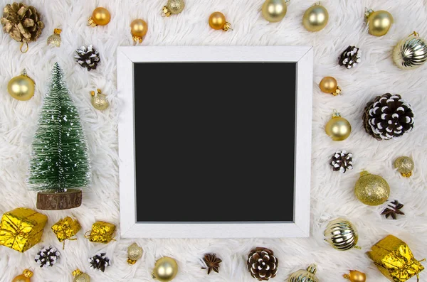 Christmas frame decorated with golden balls and a green decorative Christmas tree on a white and fluffy background. Top view