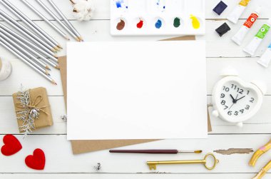 Sevgililer günü kavramı. Boş kağıt sayfası kalp ile çalar saat şeklinde. Kırmızı Kalpler ve farklı kalemler ve boya hediye kutusu beyaz ahşap zemin üzerine çizmek için. Düz yatıyordu. Mockup yazı