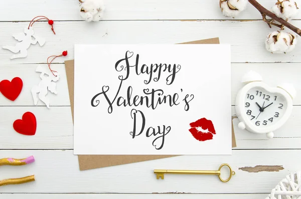 Happy Valentines Day belettering op vintage papier vel met gouden sleutel, gevormde hart wekker. rode harten op witte houten achtergrond. Flat lag. Mockup belettering — Stockfoto