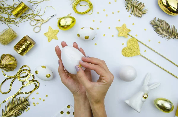 Festa da Santa Páscoa. A menina está segurando um ovo de Páscoa de porcelana decorado com círculos dourados. Composição plana . — Fotografia de Stock