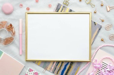 Düz altın çerçeve ve ofis malzemeleri beyaz zemin üzerine yatırın. Üstten Görünüm pembe mockup