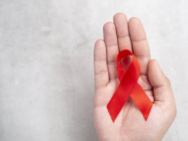 01 Aralık Avrupalı erkek el ve kırmızı kurdele Hiv Aids sembolü. Kopyalama alanı olan üst görünüm