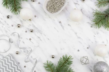 Gümüş dekoratif elementler ve xmas dallarından yapılmış düz çerçeveli Noel şenliği düzenlemesi. Beyaz mermer arkaplanda kopyalama alanı