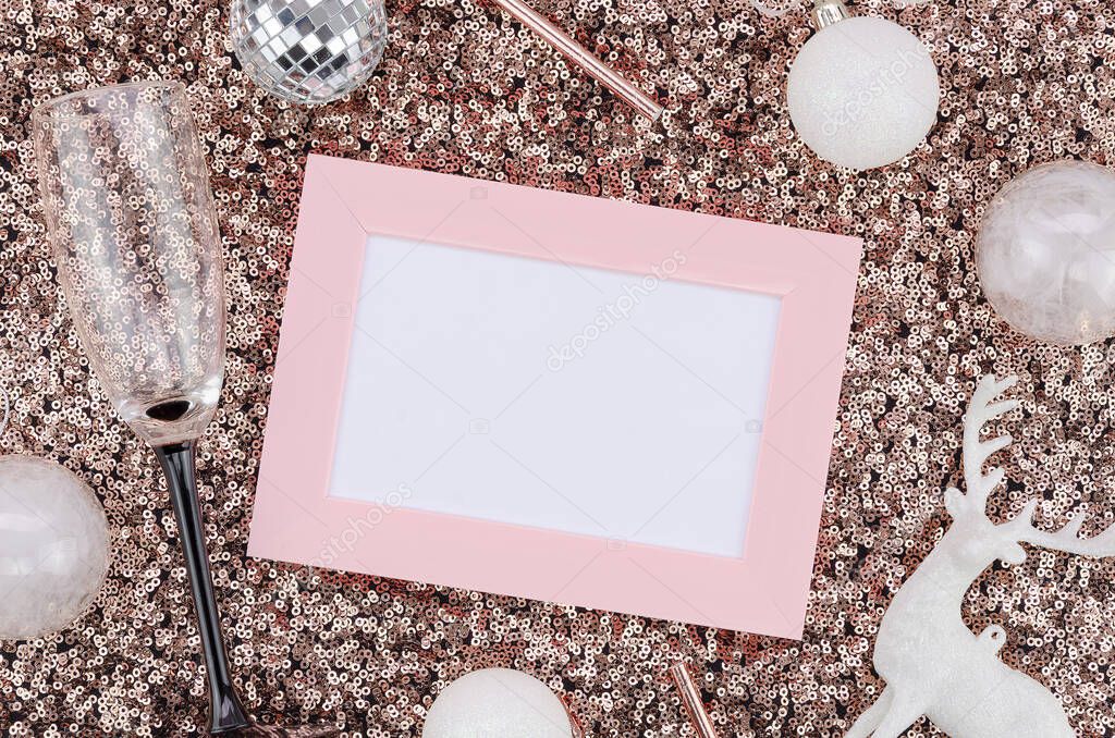 Top view frame mockup rose gold and pink New Year and Christmas flat lay. Christmas decor, copy space for text and empty champagne glasses on sequins background