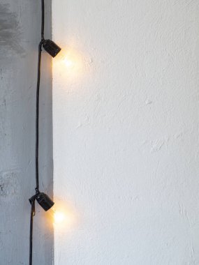 Dikey natürmort, fotokopi alanı ile donatılmış lamba çerçevesi. Beyaz bir duvarda asılı retro E27 sıcak lambalar çelengi