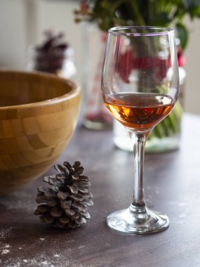 Dikey natürmort şarabı eski ahşap masada bir bardakta. Noel ya da kış ılık içecekleri etrafımızda çam kozalakları