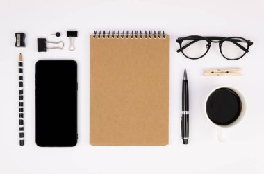 Siyah ve beyaz natürmort: akıllı telefon, not defteri, kalem, kalem, gözlük ve sipariş edilmiş ofis malzemeleri. İş aksesuarları. Üst manzara, düz uzanma.