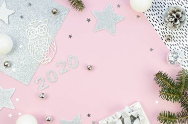 Pembe ve gümüş renginde düz bir Noel manzarası vardı. En üstteki yeşil ağaç dalları ve noel süslemeleri. 2020