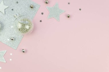 Noel süslemeleri yıldızı, cam toplar ve gümüş süsleme düz kenarlı pembe arka plan üzerinde