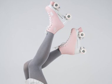 Gri taytlı kadın atletik bacakları ve pembe tekerlekli ayakkabıları var. Kızlar için fintess eğitimi