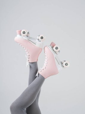 Dikey yan görünüş kadın bacaklarını dört tekerli ayakkabılı gri taytla kapatır. Bacak bacak üstüne at.