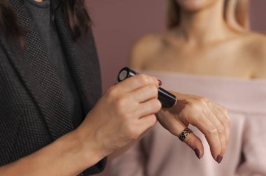 Kadın makyajcı, arka planda bulanık modelle karşılaştırmak için bronzlaştırıcı kumaş örneklerini test ediyor. Ellerini kapat.