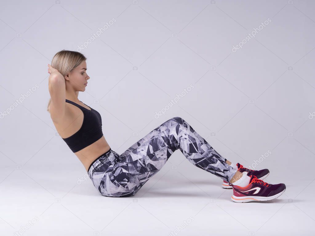 Blonde woman doing exercise abdominal crunches, pumping a press on the floor. Workout fitness aerobic side view