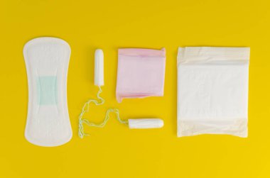 Üst manzara kadınsı pedleri, açık pedleri ve sarı arka planda tamponları paketledi. Adet döngüsü düzleşmişti