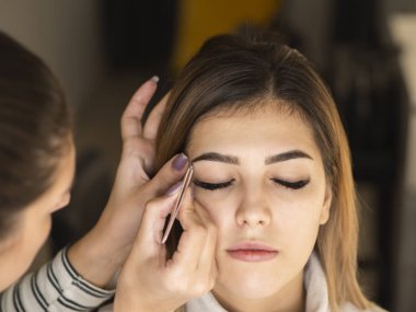 Profesyonel kaş şekli düzeltme prosedürü. Güzellik uzmanı cımbızla kaş yoluyor.