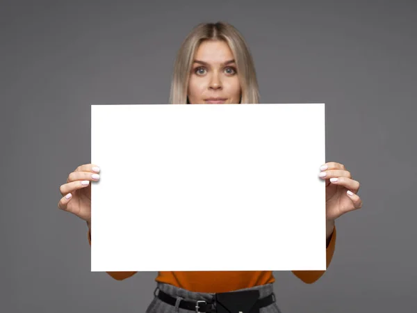 Linda jovem segurando uma folha de papel branco A1 vertical mockup com espaço de cópia para texto — Fotografia de Stock