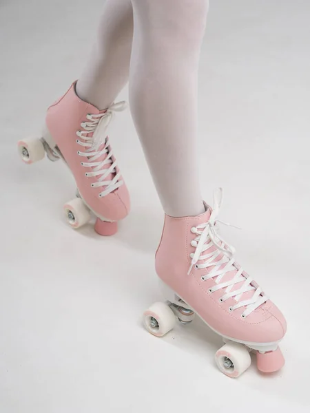 Patas femeninas con medias blancas y patines vintage rosados sobre fondo blanco, vista de primer plano —  Fotos de Stock