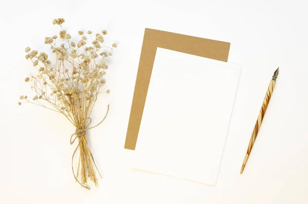 Pluma de caligrafía retro y hoja kraft de papel carta Mockup vista superior con flores secas ramo de invierno en la mesa blanca — Foto de Stock